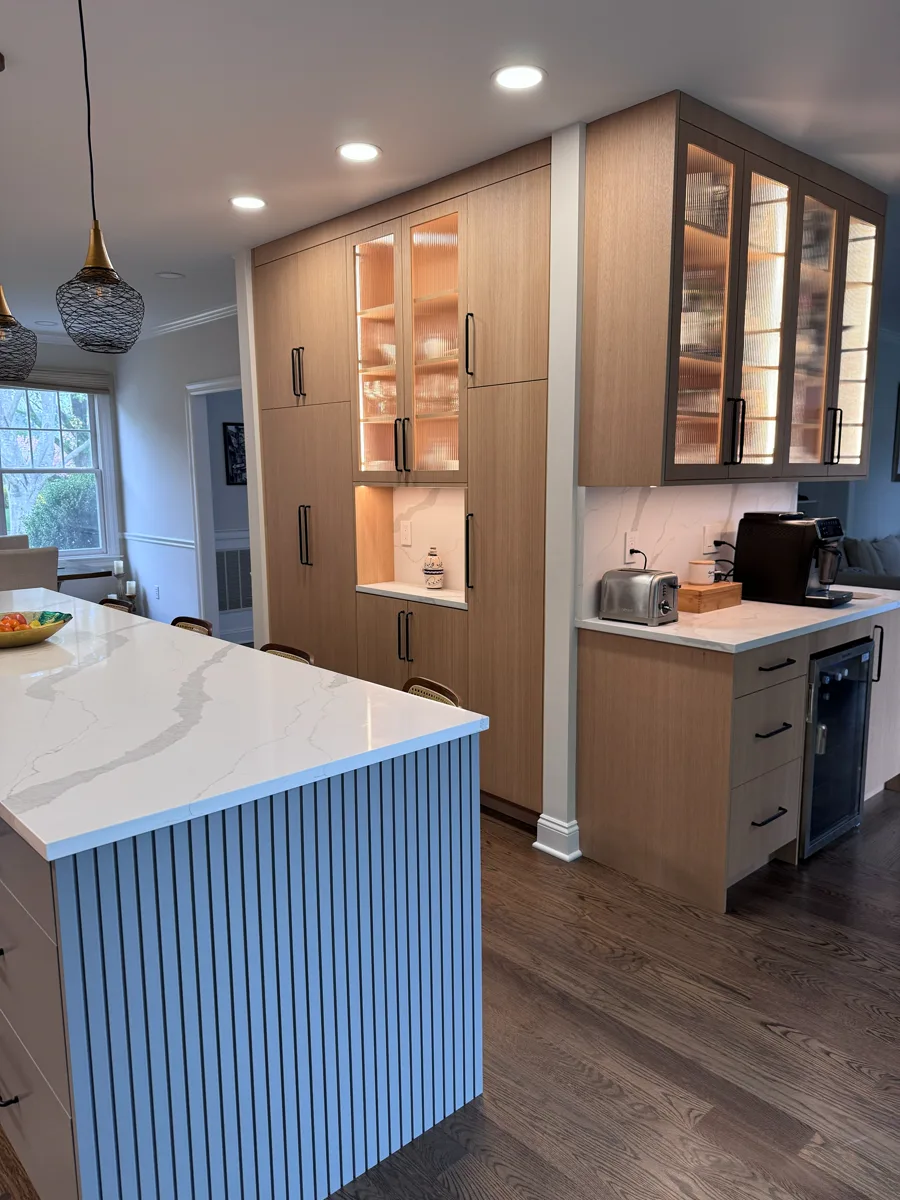 Wood kitchen cabinets with glass doors, island detail, and warm cabinet lighting
